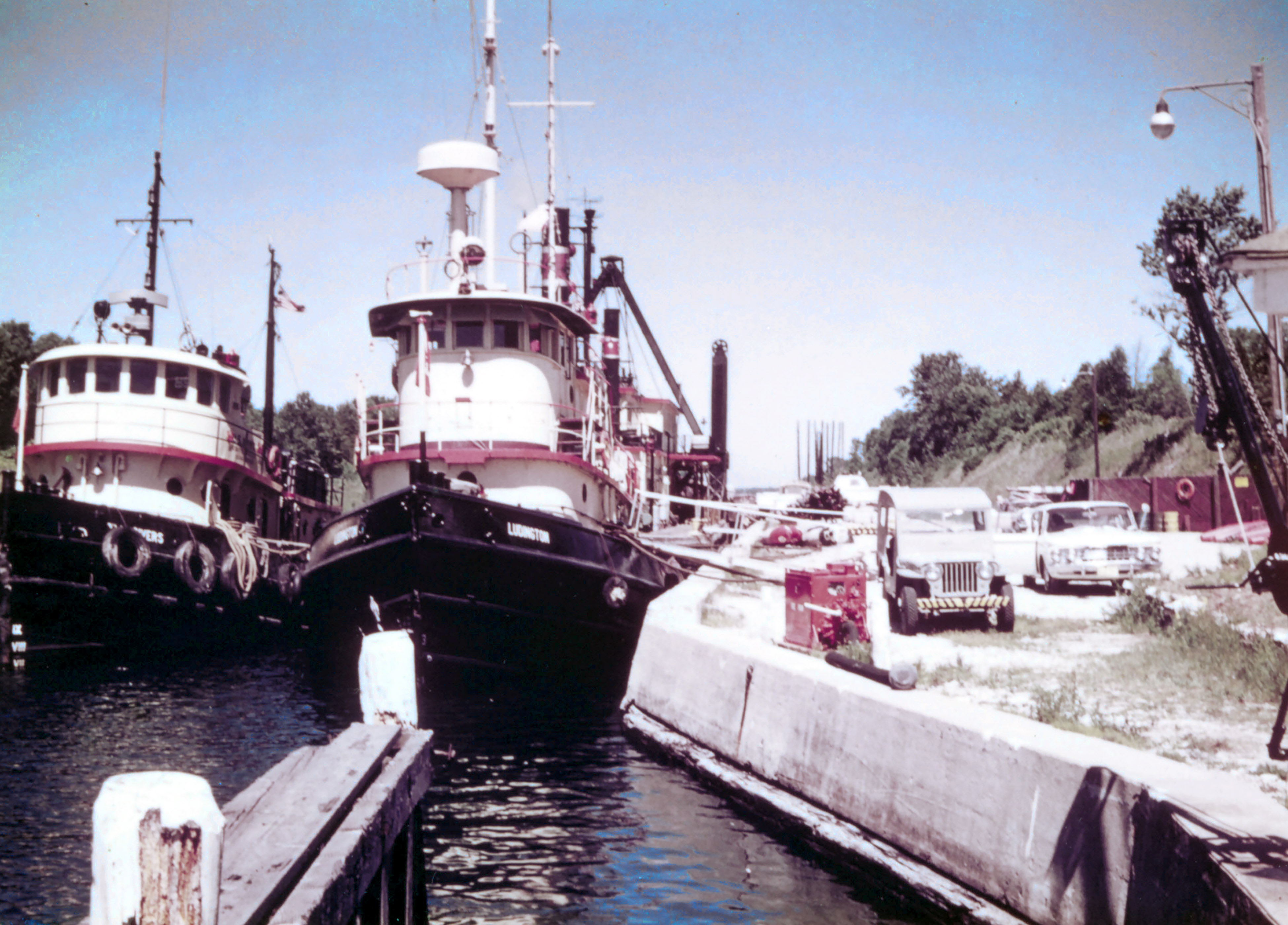 Several black and white small ships close together near a dock Several black and white small ships close together near a dock
